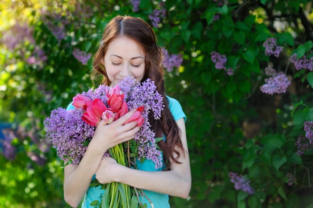 Beautiful woman with a bouquet of flowers walking in the spring park