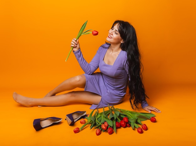 Beautiful woman with a bouquet of spring tulips on a yellow background March 8 womens day