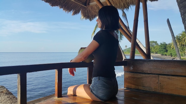 Beautiful woman with coconut enjoys sea or ocean view on vacation