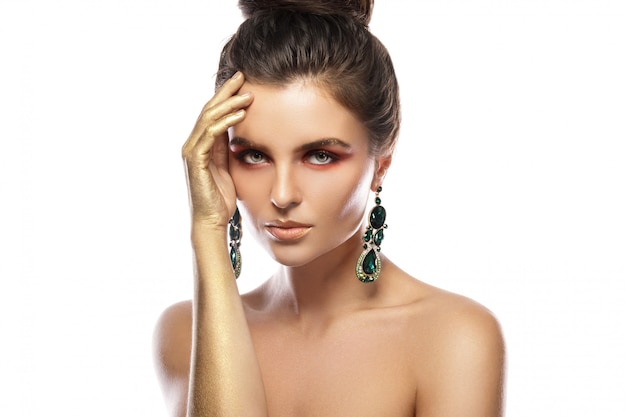 Photo beautiful woman with a colorful makeup is wearing earrings with green emeralds