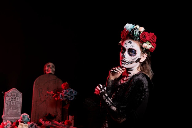 Beautiful woman with death skull make up to honor santa muerte and la cavalera catrina, mexican halloween holiday. Portraying spooky goddess of death on day of the dead celebration.