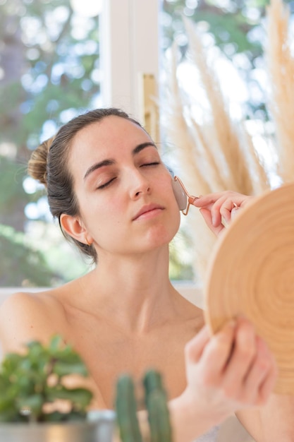 Beautiful woman with eyes closed pampering and relaxed with quartz face roller