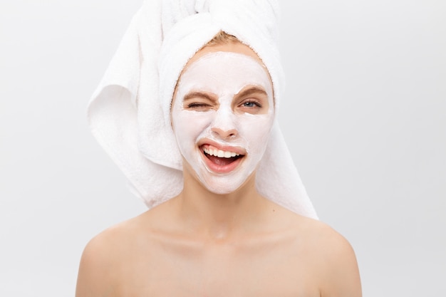 Beautiful woman with facial mask on white background