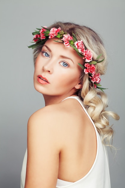 Beautiful Woman with Flowers Wreath. Blonde Curly Hairstyle and Fashion Makeup