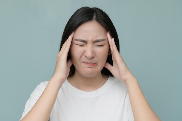 Beautiful woman with headache against blue background