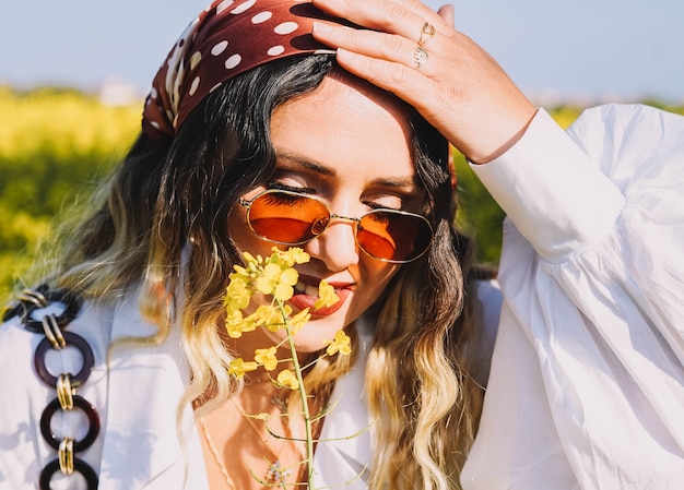 Beautiful woman with a headscarf walking on a sunny spring day through a field of flowers