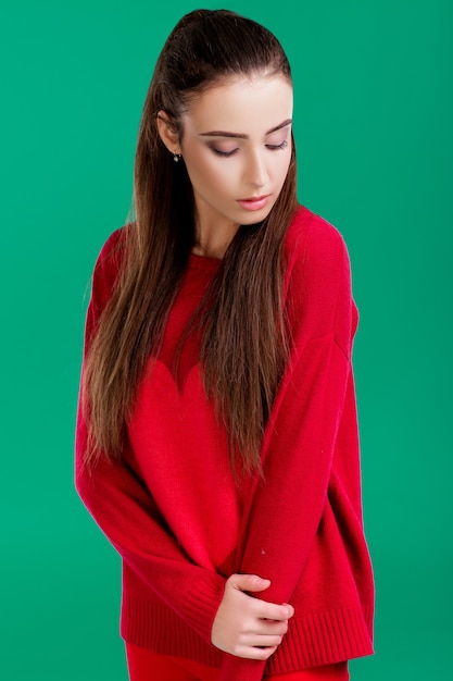 beautiful woman with long hair in red sweater on green background