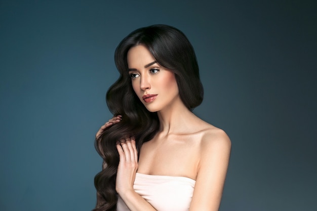 Beautiful woman with long hair, shine and curly, beauty girl female over darl gray background. Studio shot.