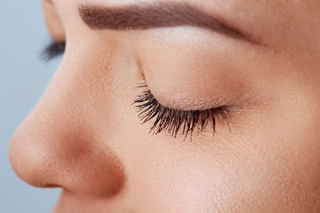 Beautiful Woman with long lashes in a beauty salon. Eyelash extension procedure. Cosmetics and makeup.