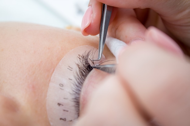 Beautiful Woman with long lashes in a beauty salon. Eyelash extension procedure. 