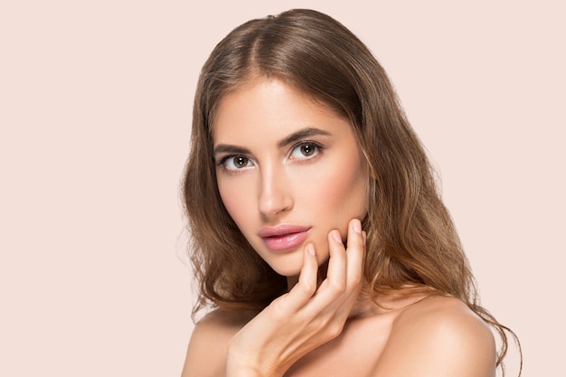 Beautiful woman with natural make up casual daily cosmetic touching her face. Color background Pink