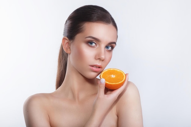 Beautiful woman with natural make up and orange on white background