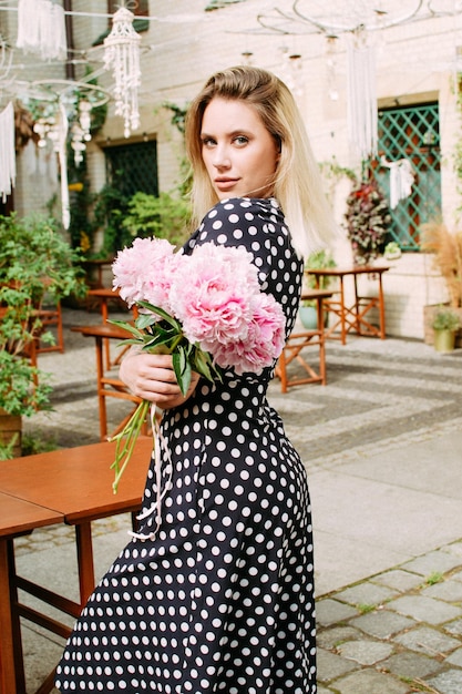 Beautiful woman with peonies on the street