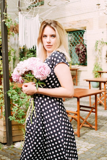 Beautiful woman with peonies on the street