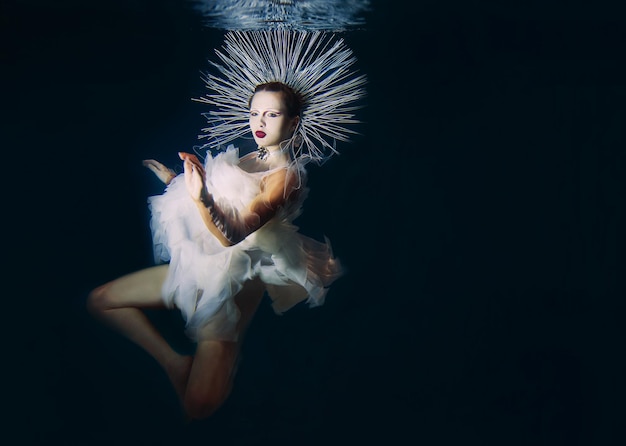 Beautiful woman with red lips and in women's jewellery underwater as the Virgin Mary