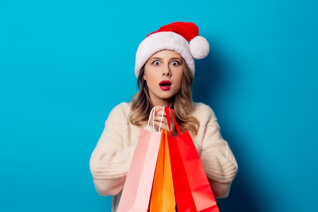 Beautiful woman with shopping bags on blue wall