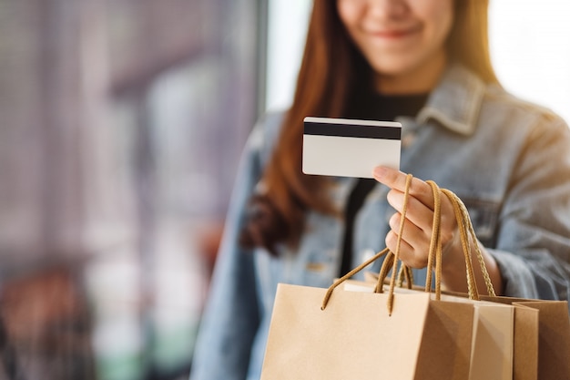 A beautiful woman with shopping bags holding and using a credit card for purchasing