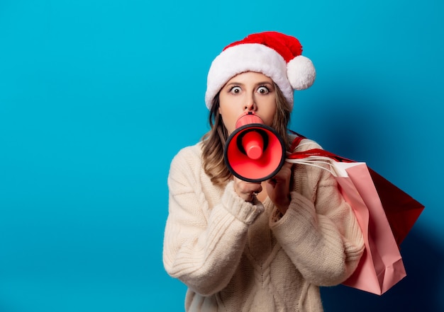 Beautiful woman with shopping bags and louder on blue wall