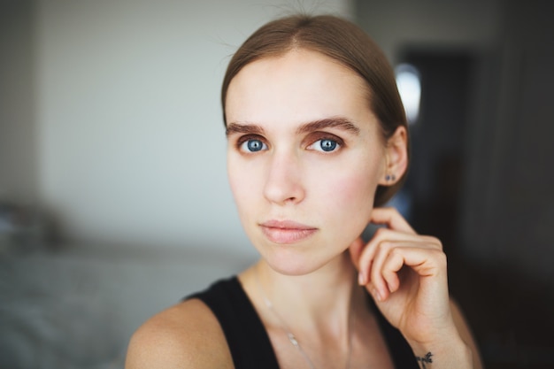 Beautiful woman with a short haircut in a black top looking at the camera. Pensive look