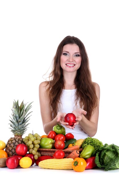 Beautiful woman with vegetables and fruits on table isolated on white