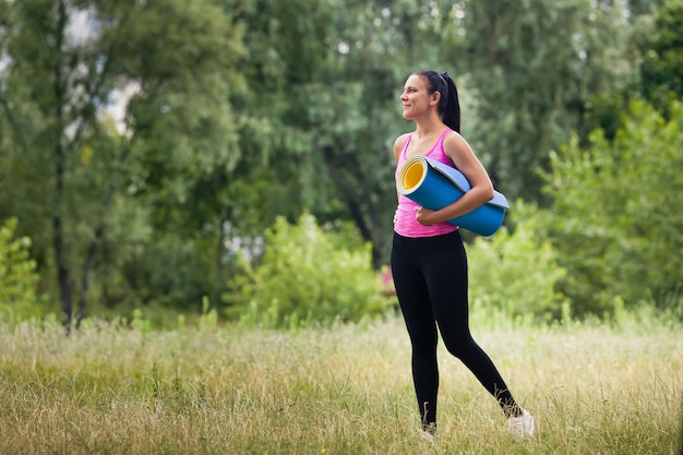 Beautiful woman with yoga mat outdoors