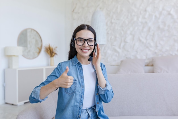 Beautiful woman working and studying at home using headset for video call smiling and looking at