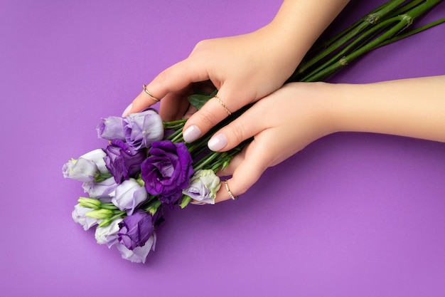 Beautiful womans hands with spring summer design on violet background Manicure pedicure beauty salon concept