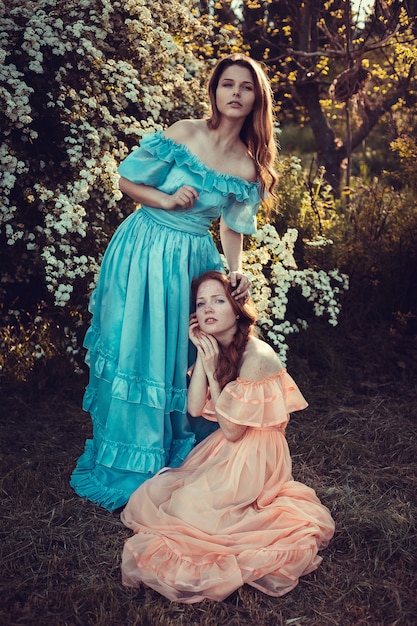 Beautiful women enjoying lilac garden, young women with flowers in green park. cheerful teenagers walking outdoor. soft light style color