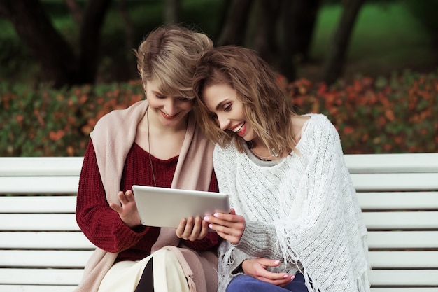 Beautiful women girls autumn using tablet outdoor