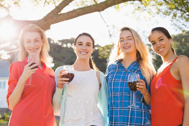 Beautiful women holding a glasses of red wine in park