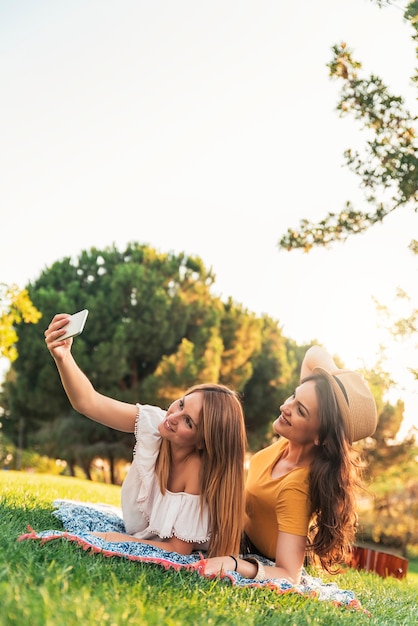 Beautiful women taking a selfie portrait in the park. Friends and summer concept.