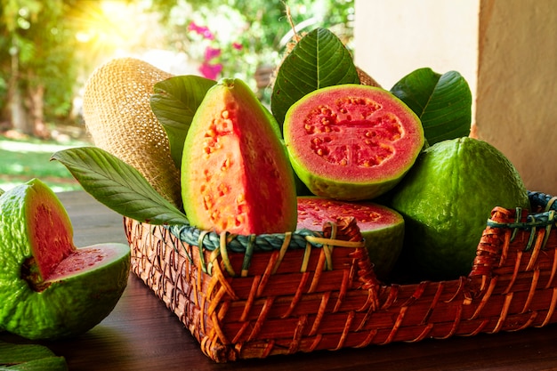 Beautiful wooden basket with red guava and some green leaves at sunset