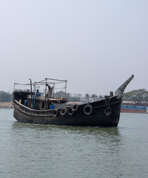 Beautiful wooden trawler on the river closeup shot Wooden fishing boat going through a river Beautiful Southeast Asian nature with a water vessel and blue sky Trawler going through the waterway