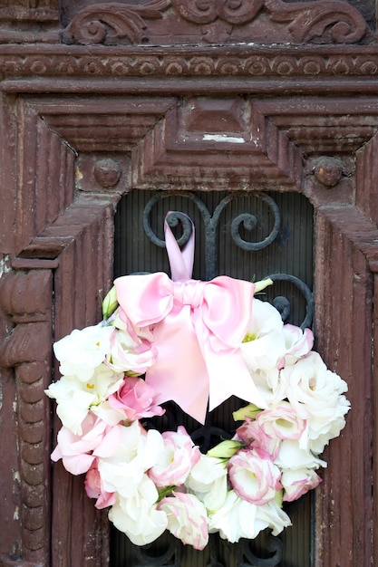 Beautiful wreath of flowers hanging on old wooden door