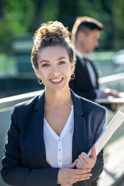 Beautiful young adult woman standing and holding documents.