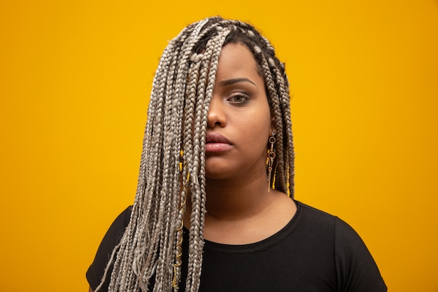 Beautiful young african american woman with dread hair on yellow