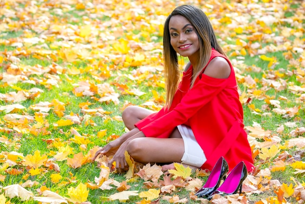 Beautiful young African girl collects autumn leaves in the Park