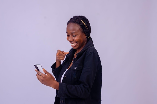 Beautiful young african lady pointing to her phone screen in excitement