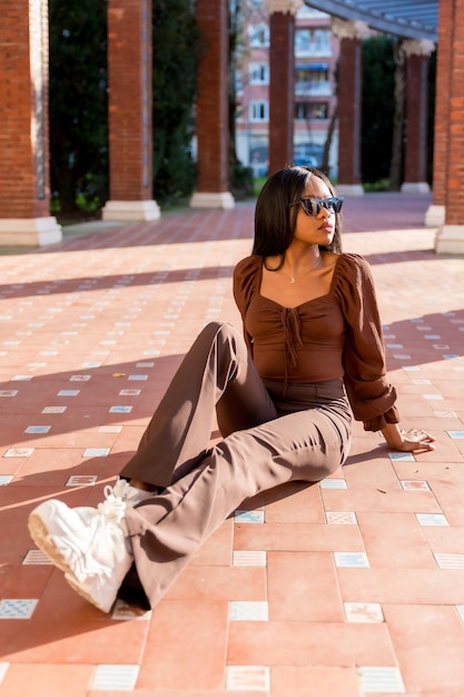 A beautiful young African woman in a park lifestyle Fashionably posed sitting on the ground at sunset