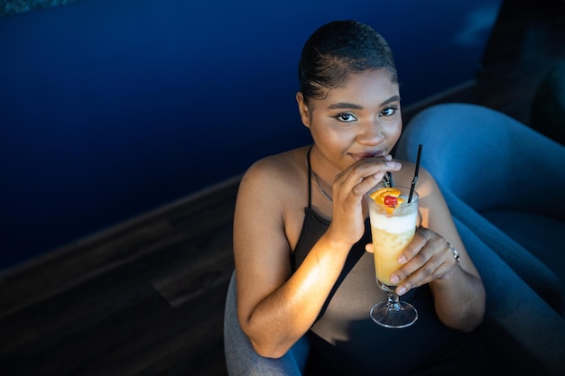 beautiful young african woman in a restaurant with a cocktail