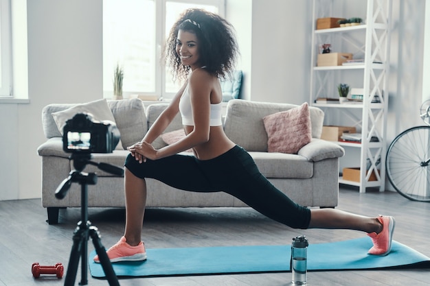 Beautiful young African woman working out and smiling while making social video