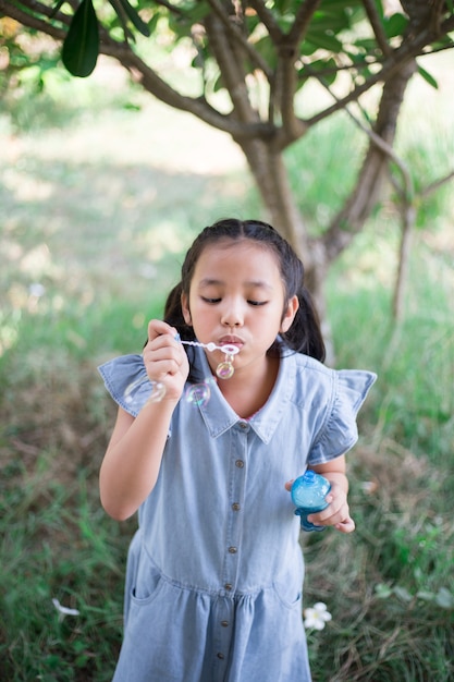 Beautiful young Asian girl blowing bubble in garden