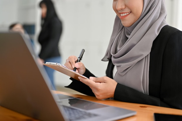 A beautiful young Asian Muslim businesswoman working at her office desk cropped image