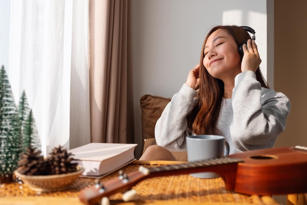 A beautiful young asian woman enjoy listening to music with headphone at home happiness and relaxation concepts