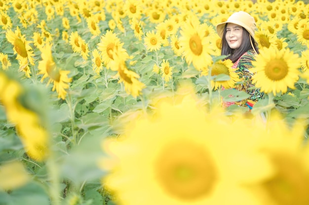 Beautiful young asian woman in a field of sunflowers in a colorful casual dress