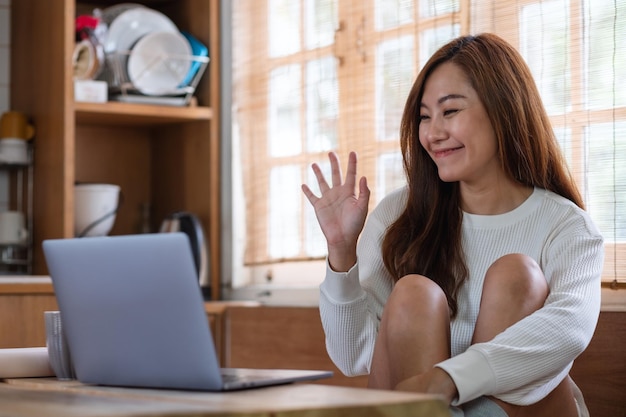 A beautiful young asian woman freelancer using laptop computer for video call and working online at home