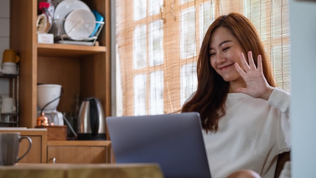 A beautiful young asian woman freelancer using laptop computer for video call and working online at home