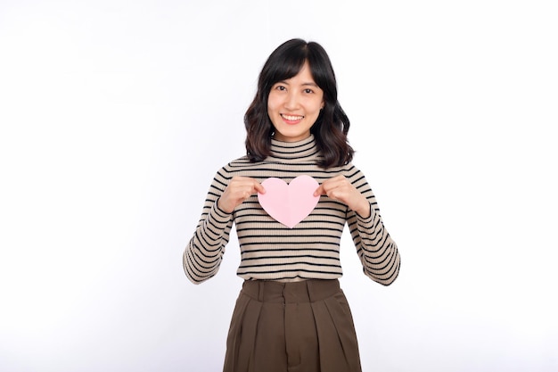 Beautiful young asian woman holding a paper heart while standing against white background Beautiful young asian woman with paper heart