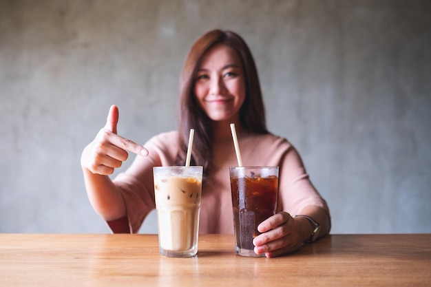 A beautiful young asian woman holding and pointing finger at a glass of iced coffee