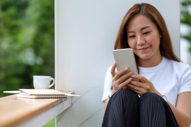 A beautiful young asian woman holding and using mobile phone in the outdoors